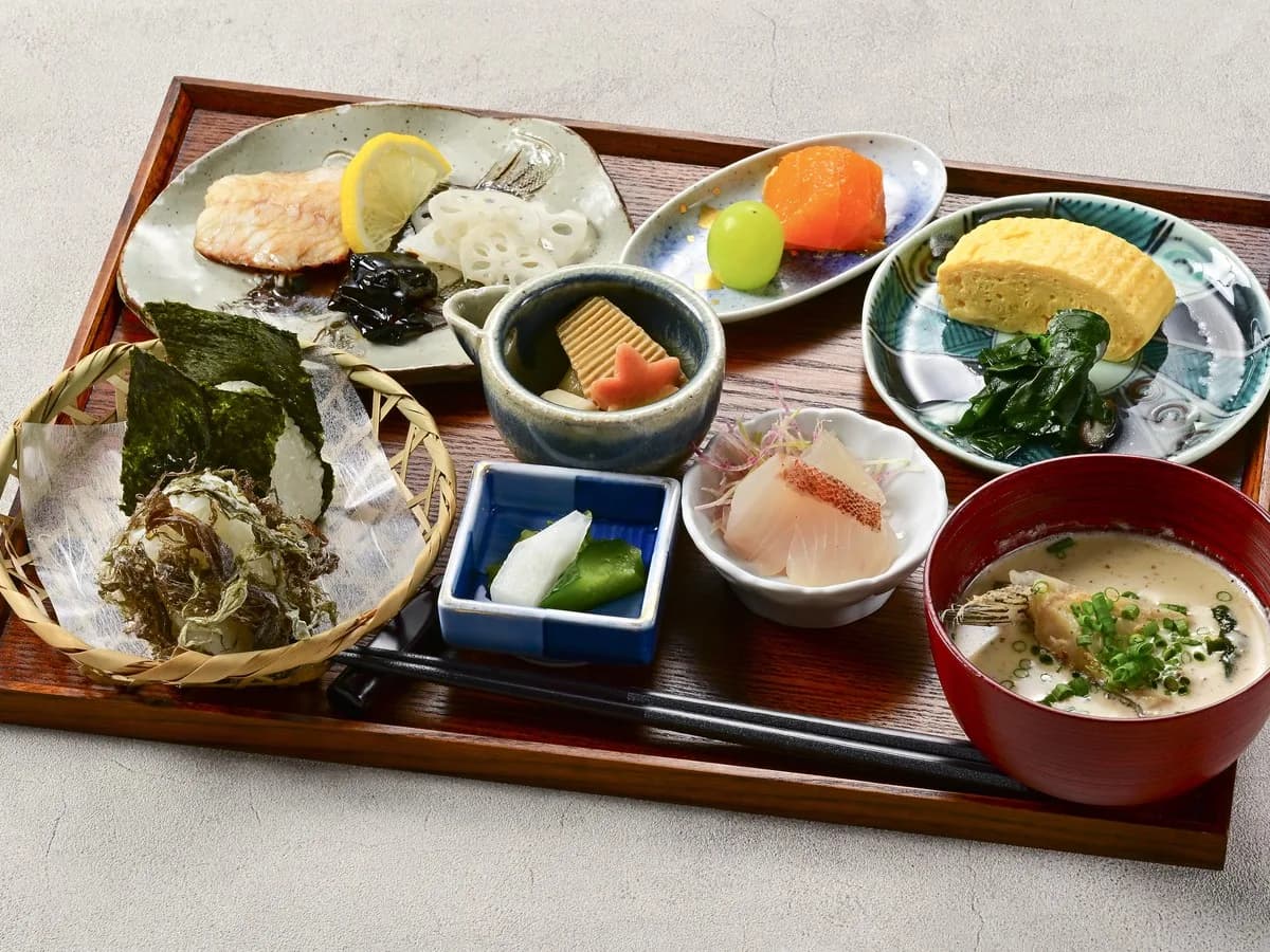 A Japanese breakfast tray with grilled fish, tamagoyaki, small dishes and miso soup