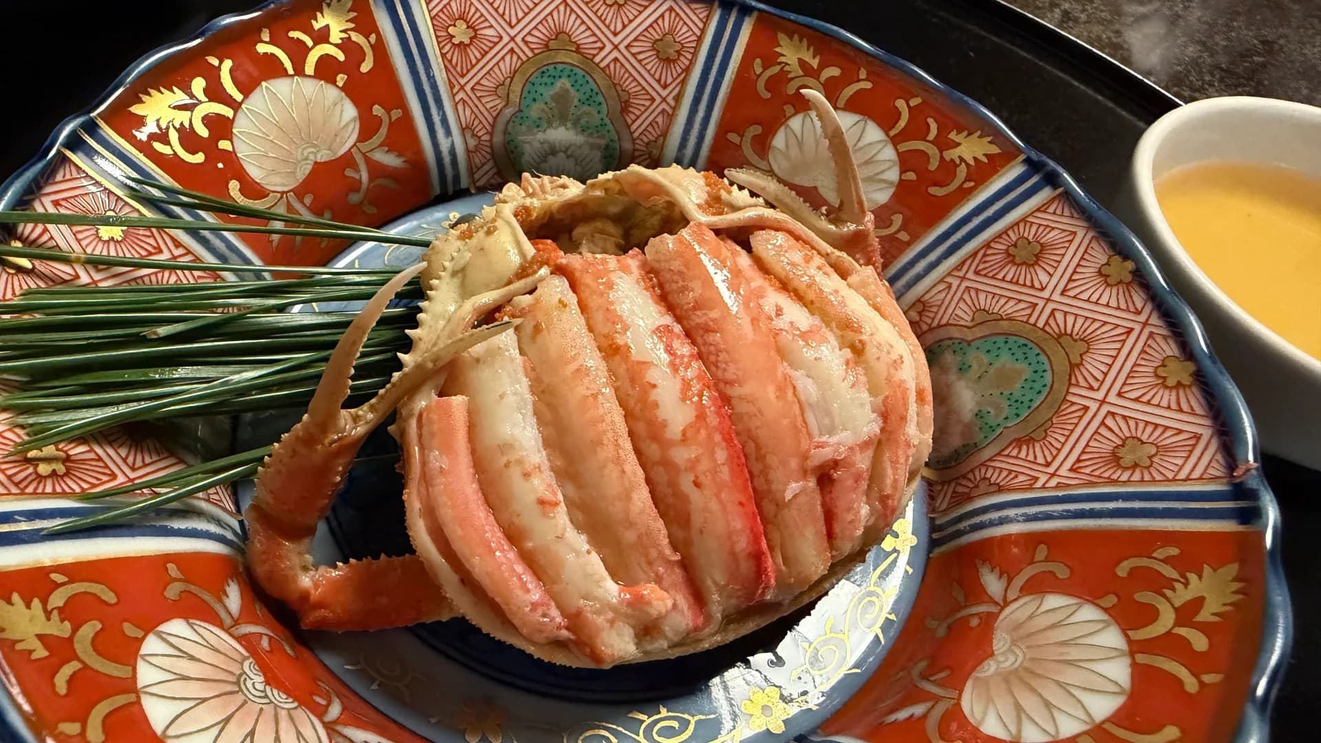 Boiled crab on a vivid Kutani-ware plate with pine needles and a crab-miso sauce