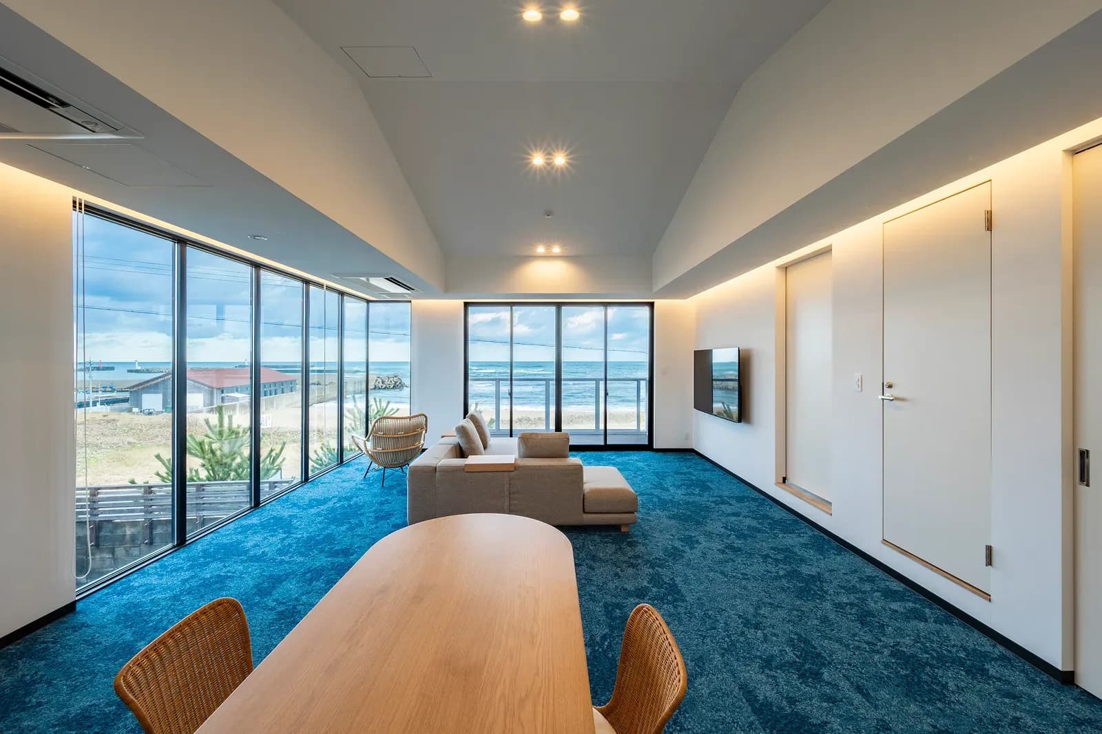 Nami no Ma living room, with the sea in the tall windows on both sides and a dining table and sofa