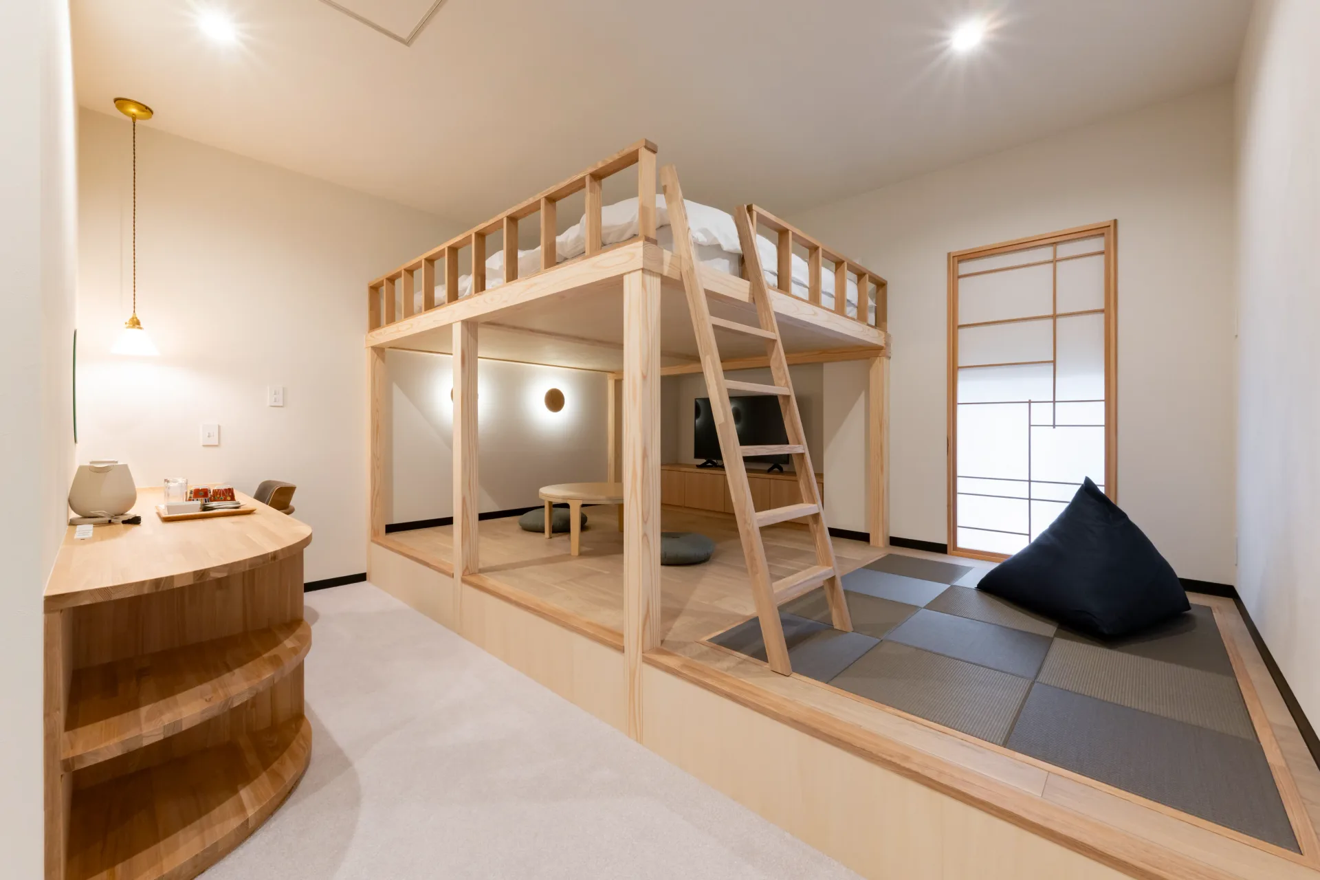 Standard room 104, a loft bed over a low round table, with checkered tatami and a beanbag cushion