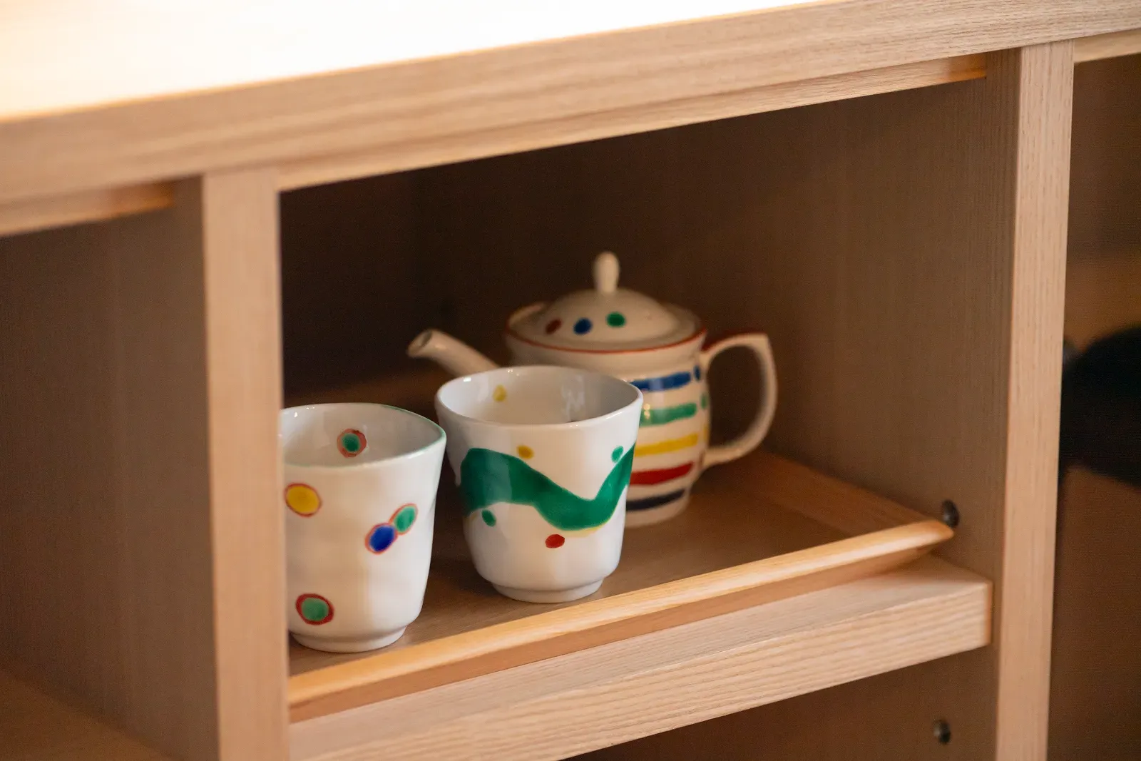 色絵の急須と湯呑。九谷を思わせる絵付けの茶器を棚に設え