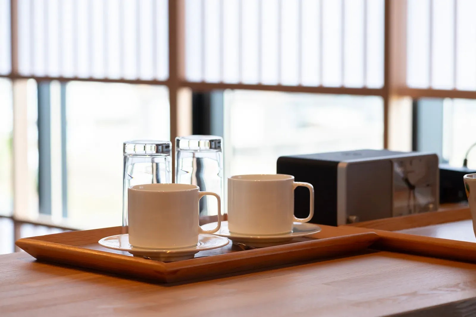 窓辺のトレイに整えたカップとグラス。湯沸かし器を備えた茶のしつらえ